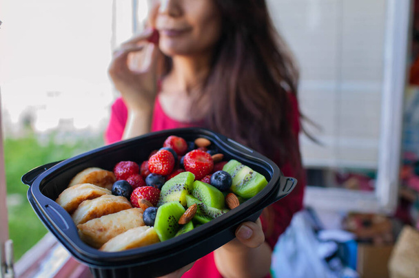 Mani della donna che tengono l'insalata fresca con frutta e bacche in piatto
 - Foto, immagini