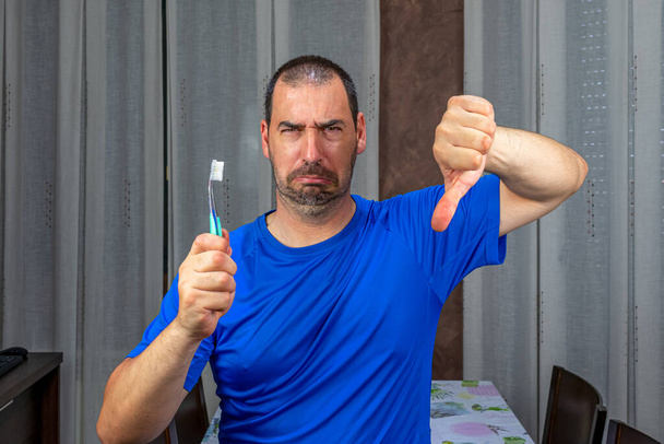 青いシャツを着た髭と短い髪の男が歯をブラッシングしている。衛生概念 - 写真・画像