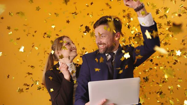 Young couple or business partners getting good news or winning the lottery. Excited celebration with confetti - Photo, Image