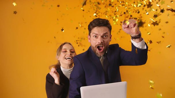 Excited young couple or business partners getting good news or winning the lottery. Celebration with confetti - Foto, Bild