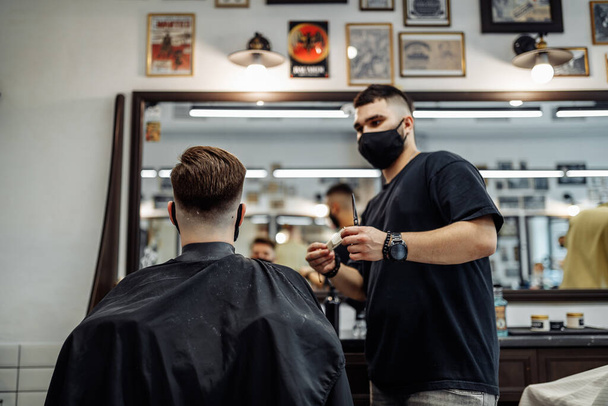 Barber makes a haircut and hair styling in a barbershop, beauty salon.  - Valokuva, kuva