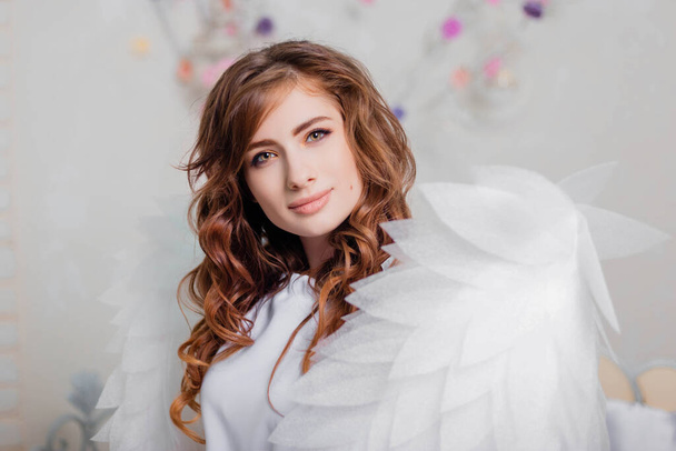 Portrait of a young woman, an angel in a white dress stands wrapped in wings. - Foto, imagen