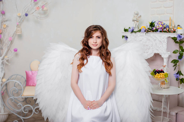Young woman angel in a white dress with wings behind her back. - Fotografie, Obrázek