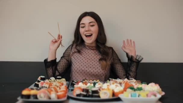 Emocionado por la cantidad de sushi en la mesa, la joven se pierde y finalmente elige un rollo. Efecto Wow. La cámara cambia de enfoque. Primer plano
 - Metraje, vídeo