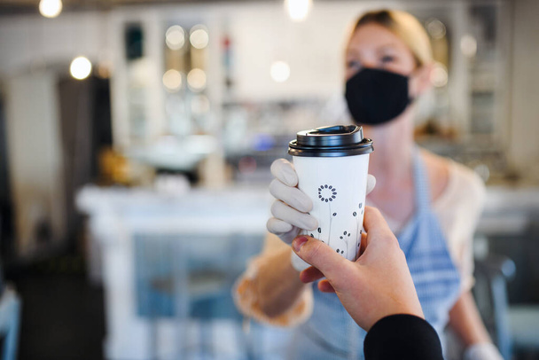 Woman with face mask serving customer, shop open after lockdown quarantine. - 写真・画像