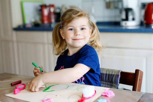 little toddler girl painting with felt pens during pandemic coronavirus quarantine disease. Happy creative child, homeschooling and home daycare with parents - Photo, Image
