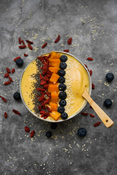 Verse mango smoothie bowl gemaakt van mango, banaan, kiwi en yoghurt, selectieve focus - Foto, afbeelding