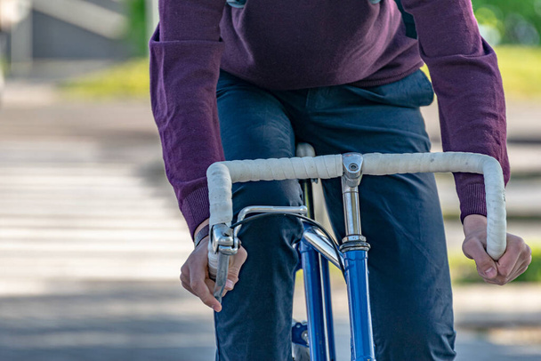 een man rijdt naar het werk op een fiets in de stad. Close-up handen op het stuur. - Foto, afbeelding