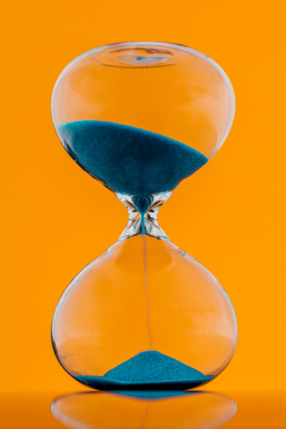 Blue hourglass on a yellow background. - Photo, Image