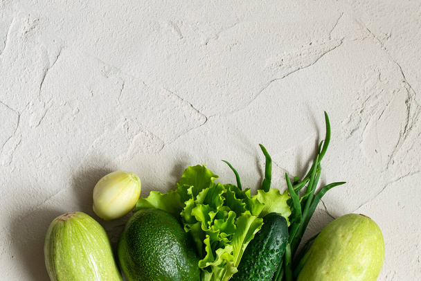 Assortment of fresh green organic vegetables. zucchini, cucumber, onion, avocado, lettuce, on a concrete background. flat lay copy space - 写真・画像