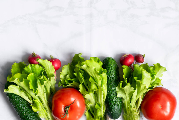 Assortment of fresh green red organic vegetables. zucchini, cucumber, onion, avocado, lettuce, pepper, tomatoes and radish on a marble background. flat lay copy space - Φωτογραφία, εικόνα
