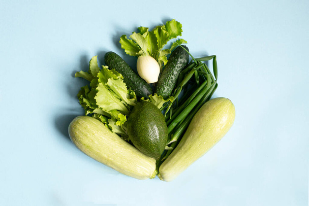 Assortment of fresh green organic vegetables. zucchini, cucumber, onion, avocado, lettuce, on a blue background. flat lay - 写真・画像