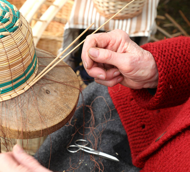руки з артрозом літньої леді, поки вона створює плетений кошик для продажу на ринку
 - Фото, зображення