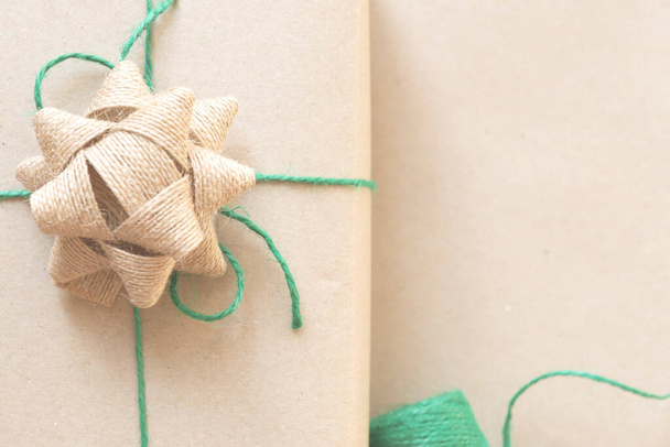 cadeau enveloppé dans du papier recyclé uni avec du fil vert sur fond beige
 - Photo, image