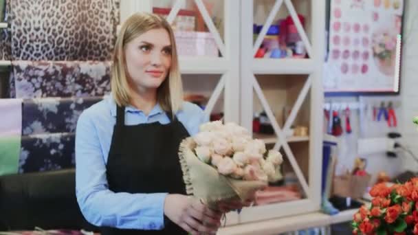 女の子の花屋は店の男の花屋の所有者に花束を販売しています - 映像、動画