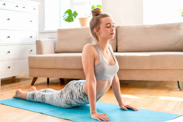 Jonge aantrekkelijke vrouwen doen yoga oefening thuis. - Foto, afbeelding