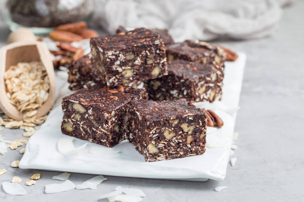 Paleo chocolate energy bars with rolled oats, pecan nuts, dates, chia seeds and coconut flakes, horizontal, copy space - Fotografie, Obrázek