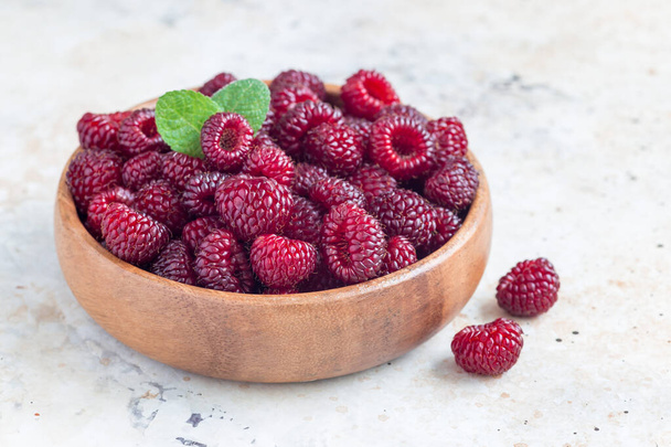 Heap of ripe wild raspberry in wooden bowl and on the table, horizontal - Foto, Imagem