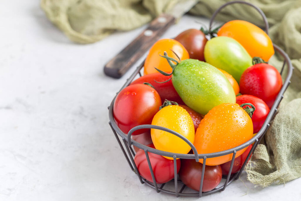 Small colorful cherry tomatoes in a metal basket, horizontal, copy space - Foto, imagen