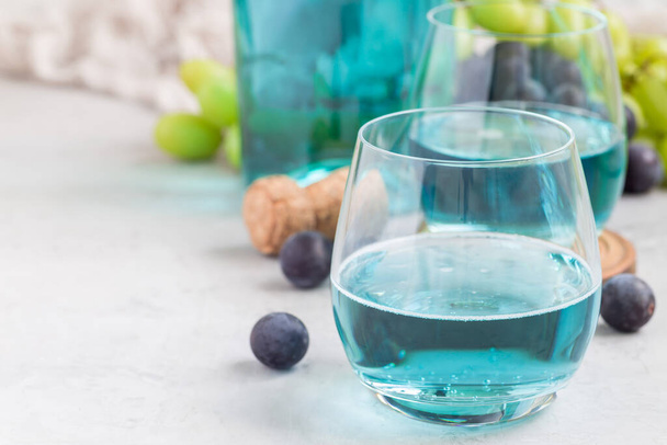 Trendy blue moscato wine in glass, green and red grape on background, horizontal, copy space - Photo, image