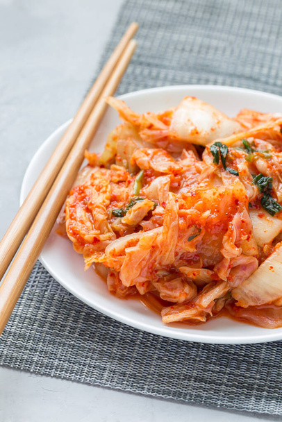 Kimchi cabbage. Korean appetizer on a white plate, vertical - Фото, изображение