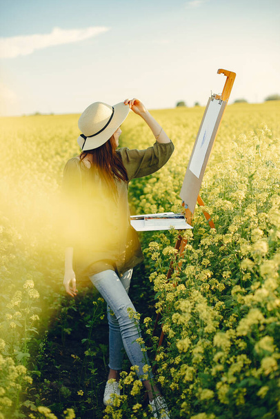 Elegant and beautiful girl painting in a field - Zdjęcie, obraz
