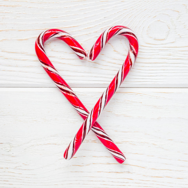Crossed peppermint candy canes on white wooden background, top view, square format - Fotoğraf, Görsel