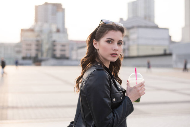 jong mooi brunette meisje is genieten met drinken op stad achtergrond - Foto, afbeelding