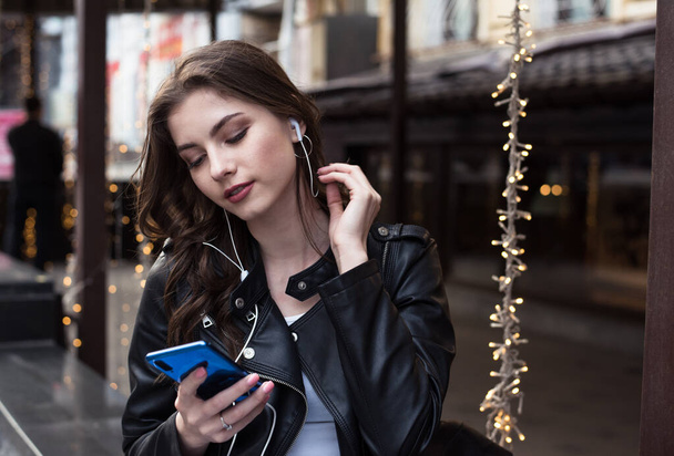 bastante blanco estudiante chica escucha romántica música en un auriculares en la ciudad
 - Foto, Imagen