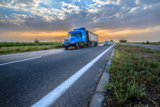 Caminhão azul na estrada ao pôr-do-sol
.  - Foto, Imagem