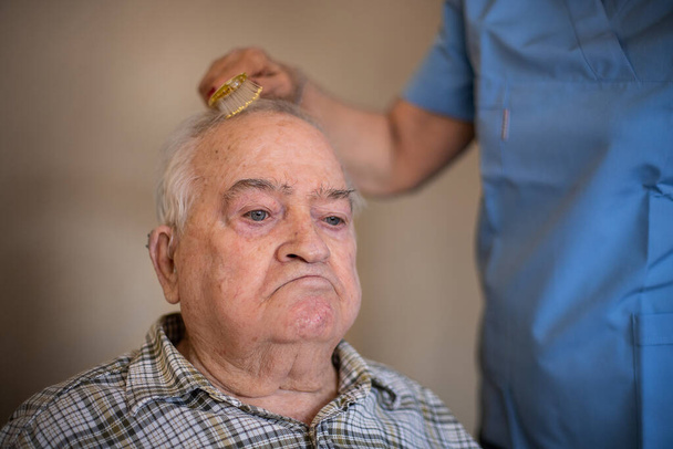 Infirmière brosse les cheveux d'un homme âgé avec un peigne, concept de soins à domicile avec une infirmière
 - Photo, image