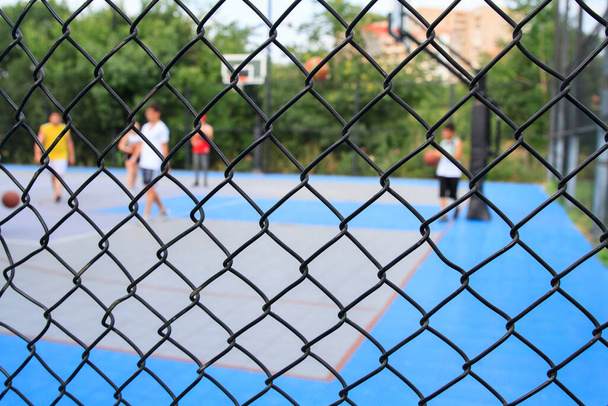 Chain link fence around basketball courts in park.  - Fotografie, Obrázek
