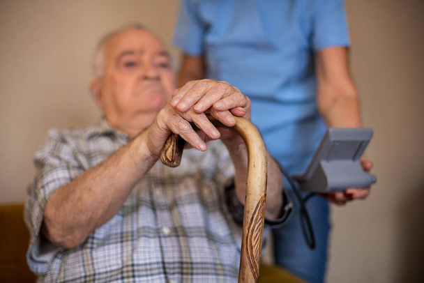 看護師は老人の血圧を測定しています看護師と一緒に家での健康管理の概念  - 写真・画像