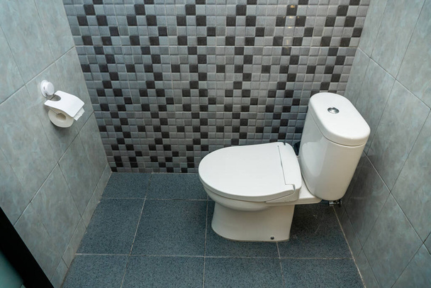 Photo of a white closed toilet in a toilet room with ceramic walls - 写真・画像