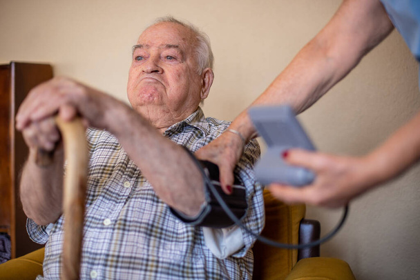 Nővér méri a vérnyomást egy idős férfi, egészségügyi koncepció otthon nővér  - Fotó, kép