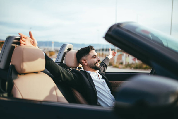 Oldalnézet boldog üzletember egy autóban a naplemente tárt karokkal - Fotó, kép