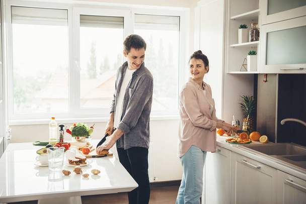 Precioso caucásico coupé sonriendo el uno al otro mientras preparan la comida juntos en la cocina
 - Foto, Imagen