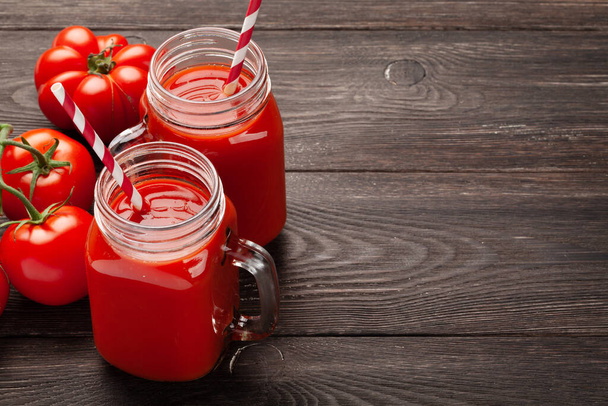 Свежий томатный сок и спелые помидоры на деревянном столе. С копировальным местом - Фото, изображение