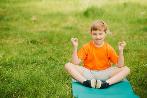 Діти займаються спортом надворі. Дитяча йога, тренування фітнесу. Дівчинка робить йогу надворі на зеленій траві. - Фото, зображення