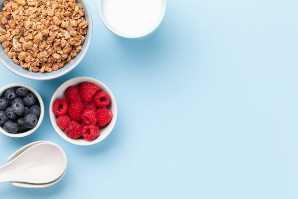 Healthy breakfast with homemade granola with yogurt and fresh berries on blue background. Top view with copy space - Photo, Image