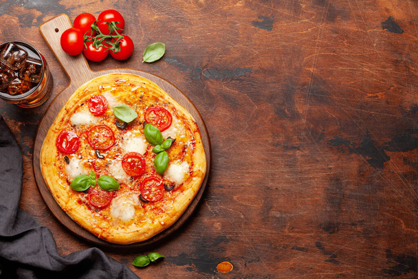 Sabrosa pizza casera con tomates de jardín y albahaca y vaso de cola con hielo. Vista superior con espacio de copia. Puesta plana
 - Foto, Imagen