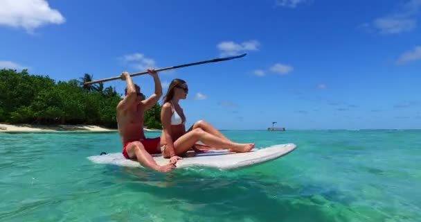 Preciosa pareja en tabla de surf surfeando en el mar claro en Bali - Metraje, vídeo