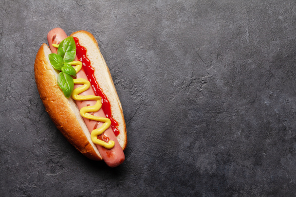 Hot dog with mustard and ketchup on stone background. Top view with copy space. Flat lay - Fotografie, Obrázek