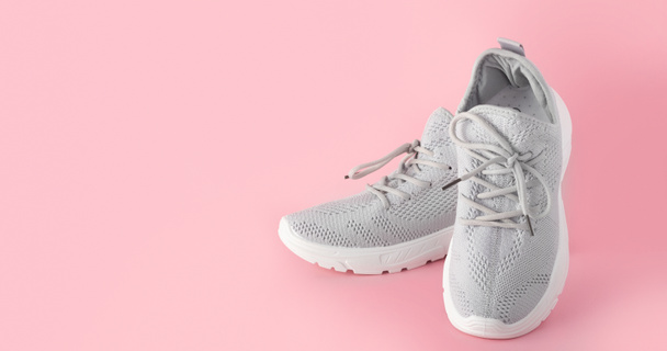 New comfortable sneakers, gray sports shoes with laces on a colored pink background with copy space. Fashion stylish, beautiful women's shoes for women and teenagers. minimalism nobody. - Photo, Image