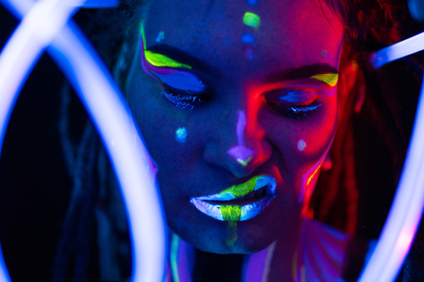 Portrait of a Girl with Glowing Tubes in Neon UF Light. Model Girl with Dreadlocks and Fluorescent Creative Psychedelic MakeUp, Art Design of Female Disco Dancer Model in UV, Colorful Abstract Make-Up - Foto, Bild