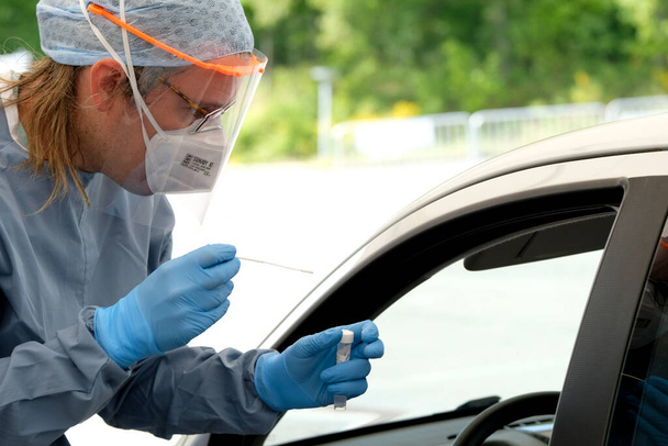 Zdravotnický pracovník provádí 5. května 2020 test na koronavirus v autokempu ve Fakultní nemocnici v Lutychu v Belgii. - Fotografie, Obrázek
