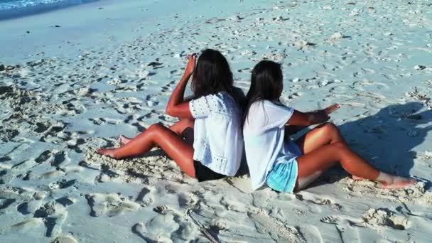 dziewczyny siedzące na piaszczystej plaży, czas dnia - Materiał filmowy, wideo