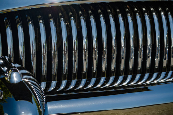 Zbliżenie do klasycznej sekcji grilla chromowanego samochodu odzwierciedlającej niejasne iskry i niebieską farbę - Zdjęcie, obraz