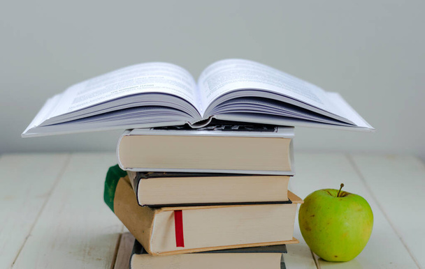 Stapel Bücher und ein grüner Apfel auf weißem Hintergrund - Foto, Bild