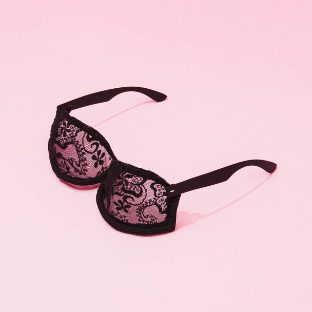 Creatief concept met zwarte kanten beha zonnebril. Minimale lingerie achtergrond. - Foto, afbeelding
